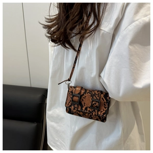 Dettaglio di una piccola borsa a tracolla con motivo a serpente e fibbie nere quadrate