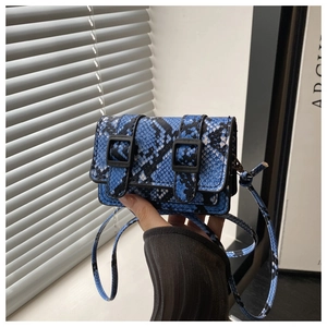 Dettaglio macro della stampa serpente blu su una mini borsa a tracolla con fibbie nere opache