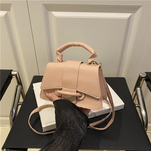 Pink lychee grain leather mini handbag with top handle and crossbody strap on white book