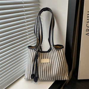 Minimalist striped canvas tote bag with leather trim and decorative spherical charms