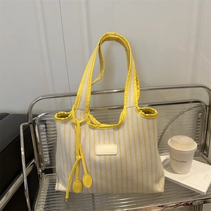 Striped canvas tote bag with yellow handles and decorative side drawstring tassels