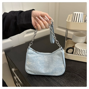 Detail of light blue rhinestone shoulder bag with silver chain and denim texture