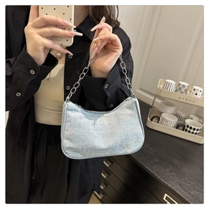 Detail of light blue denim underarm bag with chunky silver chain and sparkling rhinestones