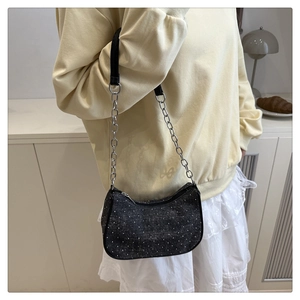 Close-up of sparkling black crossbody bag with silver chain strap on a stylish outfit