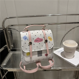 Mini white polka dot backpack with pink straps and cute doodles on a metal shelf