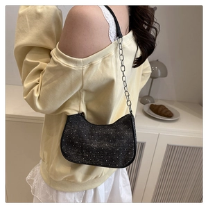 Détail du sac sous le bras en strass noirs avec chaîne argentée porté par un mannequin