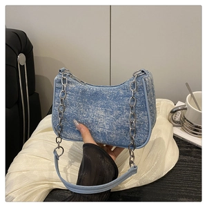 Detail of light blue denim texture shoulder bag with silver chain and leather strap