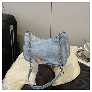 Close-up of light blue denim baguette bag with silver rhinestones and chain strap detail