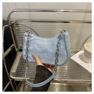 Détail du sac hobo en jean bleu clair avec strass argentés et bandoulière en chaîne métal