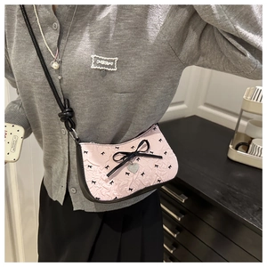Side view of pink bow crescent bag with heart tag on a model for casual summer style