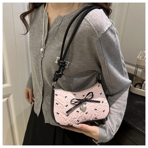 Detailed side view of pink bow baguette bag with embossed patterns and metal heart charm