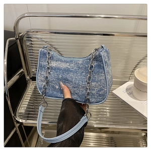 Détail du sac baguette en denim bleu avec fini pailleté argenté et chaîne en métal