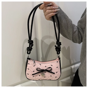 Detailed shot of pink embossed crescent bag with black bow print and heart charm