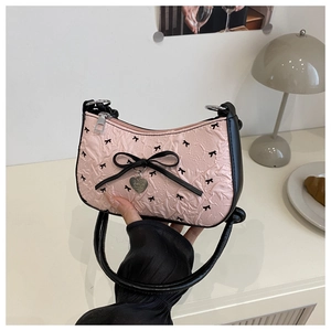 Detailed shot of pink pleated underarm bag with black bow and silver heart charm