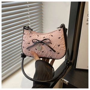 Detail of pink pleated fabric underarm bag with black bows and heart pendant