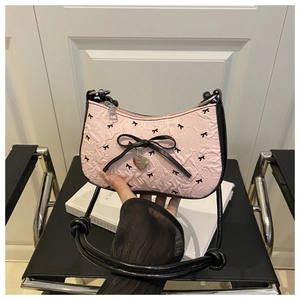 Detail of pink hobo bag with black bow prints and silver heart-shaped metal pendant