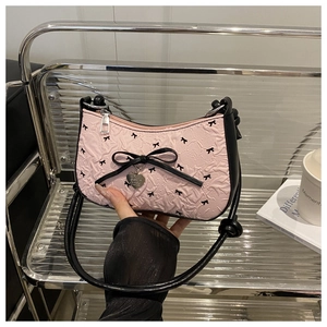 Detail of pink crescent underarm bag featuring black bows and silver heart charm