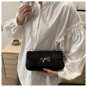 Détail d'un sac à bandoulière noir chic avec boucle nœud argentée et élégante chaîne en métal