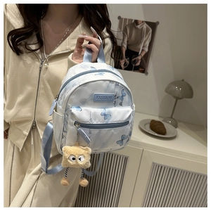 Details des Mini-Rucksacks mit Schmetterlingsprint, Plüsch-Anhänger und Logo