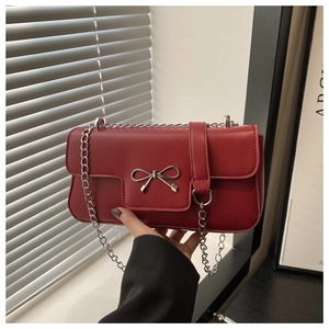 Détail du sac en cuir bordeaux avec nœud argenté et bandoulière en chaîne