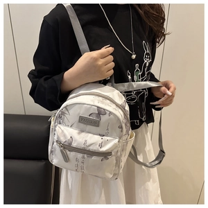 Detailaufnahme eines weißen Mini-Rucksacks mit Schmetterlingsdrucken und Kunst-Kalligraphie
