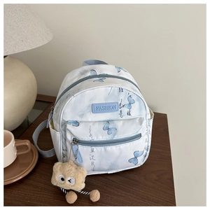 Detail des weißen Mini-Schmetterlings-Rucksacks mit blauen Trägern und Plüschtier