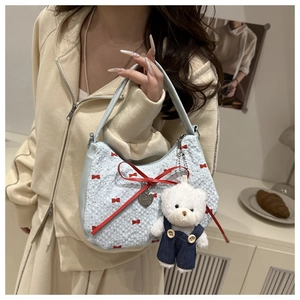 Detail of light blue quilted tote with red bow print and plush bear charm pendant