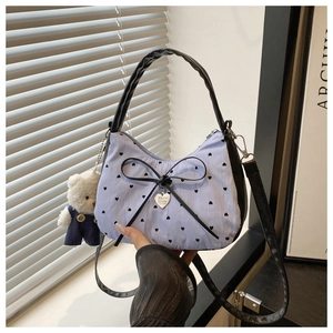 Detail of sweet striped handbag with heart patterns, bow detail, and plush bear charm