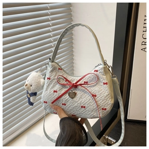Detail of white bubble textured handbag with red bows and plush bear charm accessory
