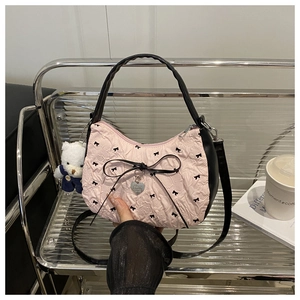 Detail of pink pleated handbag with black bows, leather trim and bear pendant