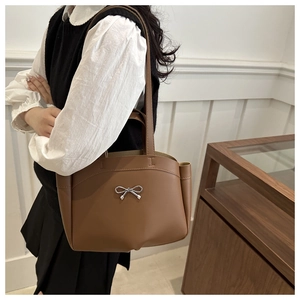 Détail d'un sac cabas en cuir marron avec nœud argenté et doubles bandoulières