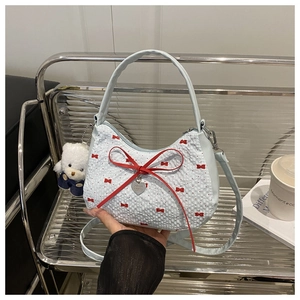 Detail of light blue quilted handbag with red bows and a cute white bear pendant