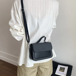 Minimalist black flap handbag with textured grid design and adjustable shoulder strap