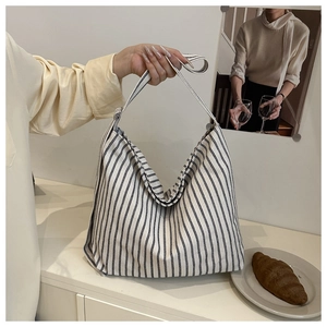 Macro detail of high-capacity striped canvas tote bag with wide durable shoulder straps