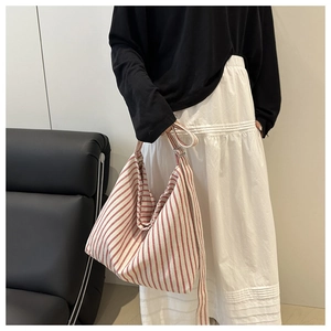 Detail of red and white striped canvas tote bag showing large capacity and shoulder strap