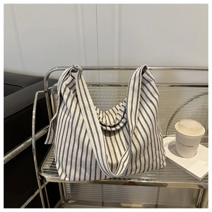Close-up of black and white striped canvas tote bag texture on a modern display stand