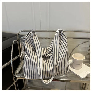 Detail of blue and white striped canvas tote bag hanging on a modern metal rack