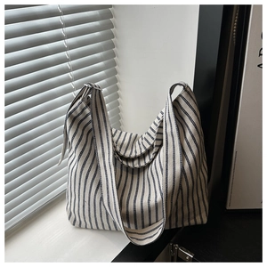 Detailed view of blue and white striped canvas tote with textured fabric and wide shoulder strap