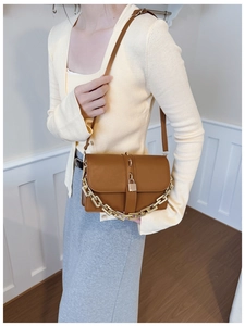 Détail d'un sac bandoulière marron en similicuir avec chaîne dorée et boucle élégante