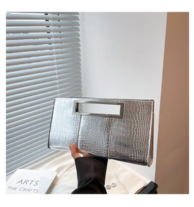 Close-up of silver crocodile embossed clutch bag with unique hollow rectangular metal handle