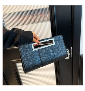 Detail of elegant black crocodile pattern clutch bag with large silver metal handle