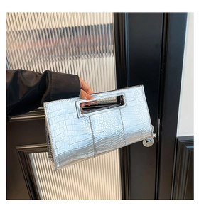 Detailed view of silver crocodile embossed handbag with metallic finish and cut-out handle