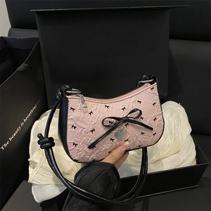 Pink bow-print crescent underarm bag with black heart pendant and knotted shoulder strap
