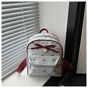 Close-up of gray mini backpack with red bow prints and silver heart pendant detail