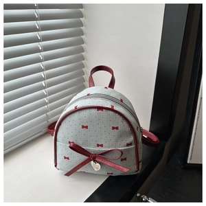 Detailed macro of a light blue polka dot mini backpack with a red leather bow decoration