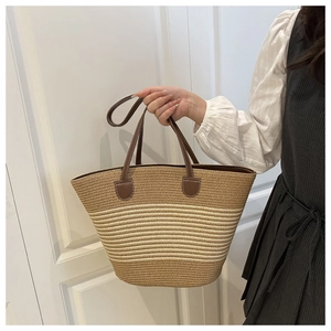 Detail of the woven texture and reinforced brown leather straps on striped straw tote bag