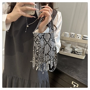 Detailed close-up of a faux leather handbag with snakeskin pattern and long tassels