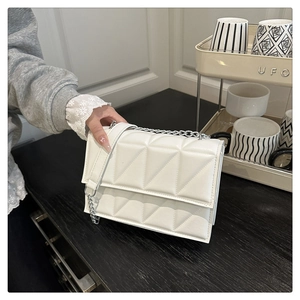 Detail view of white quilted crossbody bag with silver chain strap and flap closure