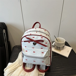 Mini floral backpack with red bows and heart tag on a stylish wooden table setting