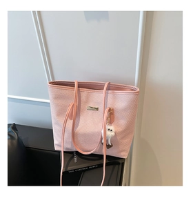 Détail du sac cabas rose tissé avec garniture métallique et pendentif peluche blanc